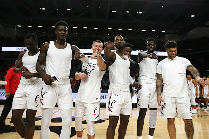 Cincinnati Bearcats guard Keith Williams (2), forward Trevon Scott (13), guard John Koz (32), guard Trevor Moore (5), forward Prince Gillam Toyambi (24), forward Mamoudou Diarra (20) and guard Jarron Cumberland (34) admire their American Athletic Conference basketball tournament champion rings before the first half of a college basketball game against the UNLV Rebels, Saturday, Nov. 30, 2019, at Fifth Third Arena in Cincinnati. Unlv Rebels At Cincinnati Bearcats Nov 30